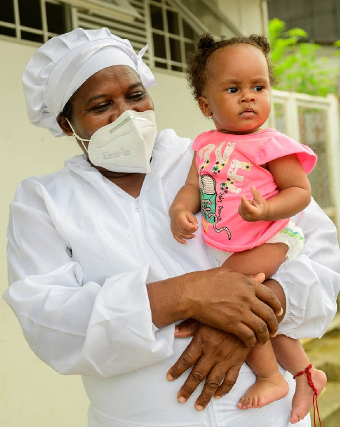 Health worker holding a baby in the Caribbean